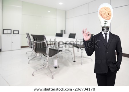 businessman have brain inside a light bulb posed gesturing ok sign while standing in a modern office idea concept for creativity