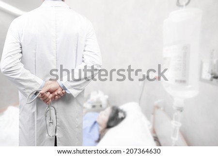 rear view image of doctors with stethoscope in a hospital pose arms crossed behind back looking at nurse pushing stretcher gurney bed in labour room of hospital corridor with female patient pregnant