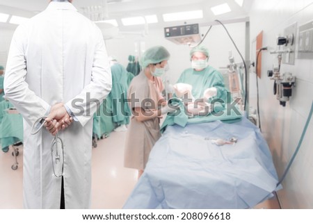 rear view image of doctors with stethoscope in labour room pose arms crossed behind back looking at team surgeon in operating room