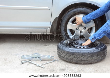 woman removing a wheel  car on the roadside