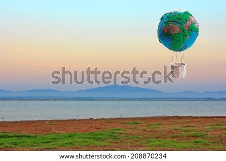 globe hot air balloon basket in ecology concept against mountains and fog at sunrise