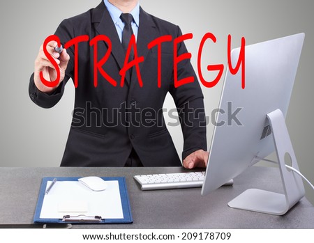 businessman writing word strategy on virtual screen and using computer worker at desk