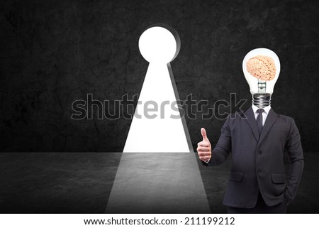 businessman thumb up and head brain inside a light bulb standing front of key hole on old grunge black wall