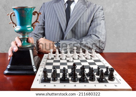 businessman and trophy from playing chess in strategy and goal concept against concrete wall