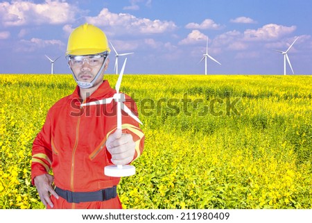 technician with holding wind turbine in a flower field eco power concept