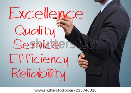 Businessman writing with pen about excellence quality service efficiency and reliability for success on virtual screen