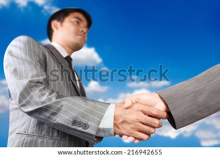 business handshake at meeting against blue sky partnership concept