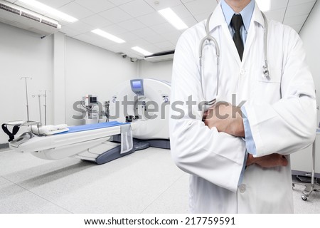 portrait of mature doctor at computed tomography or computed axial tomography scan machine in hospital room