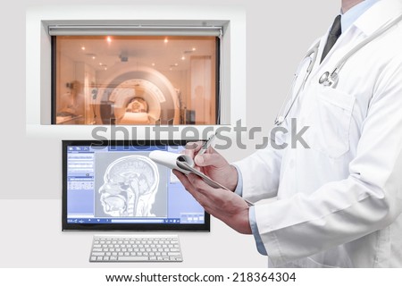 doctor writing clipboard looking at magnetic resonance image (MRI) of the brain on screen for diagnosis in operation room