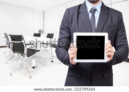 Businessman holding a tablet computer for presentation something with an screen at conference room in modern office interior