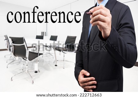Businessman writing word conference with pen on virtual screen at conference room in modern office interior