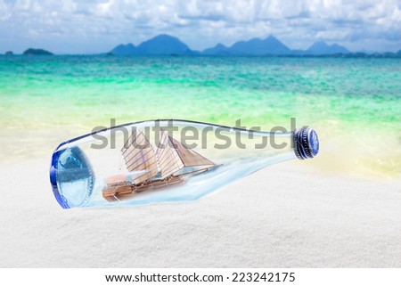 Blue glass bottle on sand and tropical sea with junk boat The midst variance weather inside lying on the beach  Conceptual image