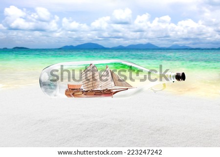 Vintage old bottle with junk boat inside lying on the beach  Conceptual image