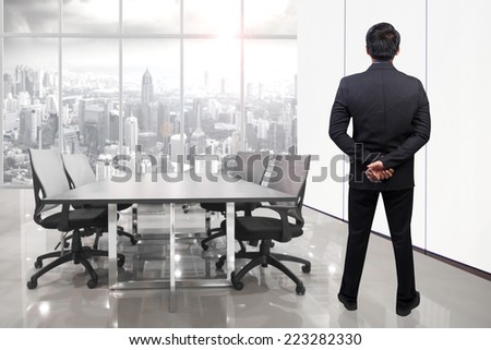 rear view of businessman looking to the future at conference room in modern office interior on high building