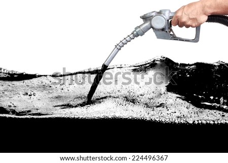 Hand holding a classic fuel nozzle pumping a black fossil fuel liquid crude in a tank of oil Industry isolated on white background with clipping path