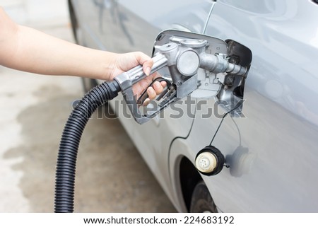 Woman hand holding a classic fuel nozzle pumping a gasoline fuel liquid refilling the car