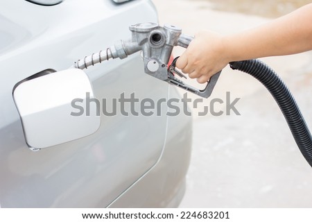 Woman hand holding a classic fuel nozzle pumping a benzine fuel liquid refilling the car
