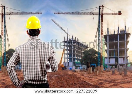 civil engineer working in building construction site against sunset sky with crane construction