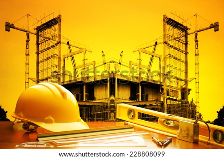engineer working table plan building model and writing tool equipment against building construction crane with beautiful sunset