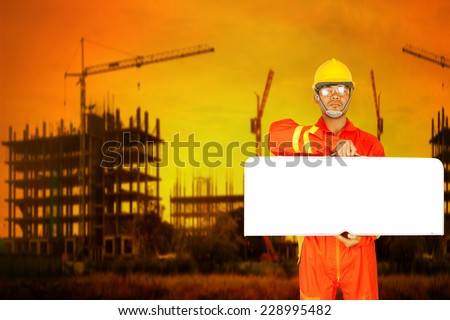 technician in uniform holding toolbox as blank white banner with copy space for your text working at high building construction site against beautiful sunset