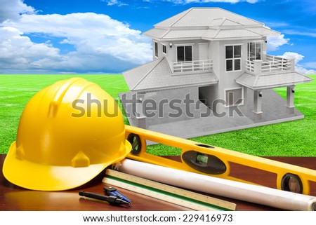 engineer working table plan building model and writing tool equipment and blueprints  against house structure  in concept of real estate and engineering
