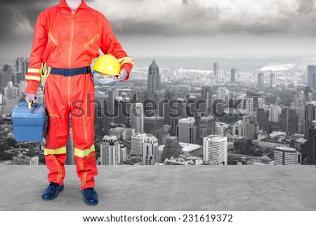 technician in uniform holding toolbox working at high building construction site against urban scene balcony over looking city dusky before rain falling