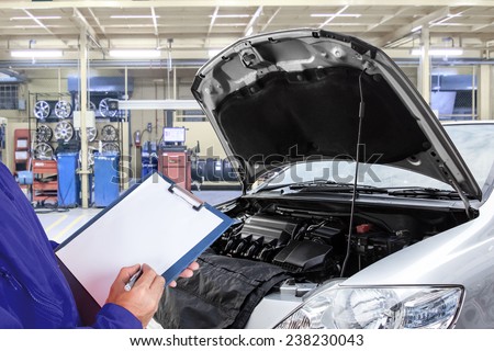 Close-up of mechanic maintaining car record on clipboard at the repair shop
