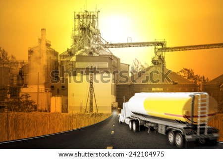 Truck with fuel tank in motion blur on the highway into corn dryer silos and beautiful sunset sky in concept of industrial and agriculture