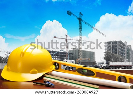 engineer working table plan building and writing tool equipment against crane and building construction and beautiful sky in concept of real estate and engineering