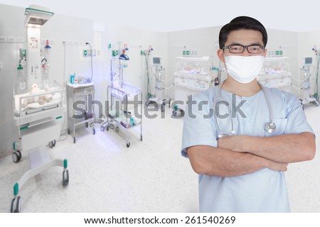 surgeon pose arms crossed behind back in aided the recovery room with newborn in incubator at hospital