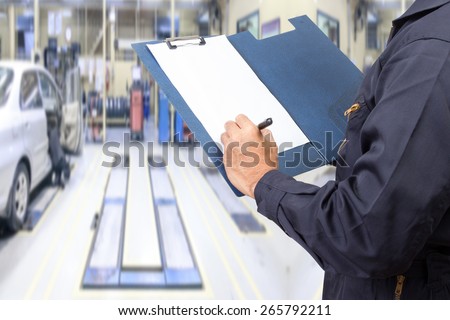 mechanic holding a clipboard of service order for maintaining car at the repair shop