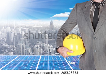 business man holding helmet and solar energy panels on high building against beautiful sky with in concept ecology and real estate