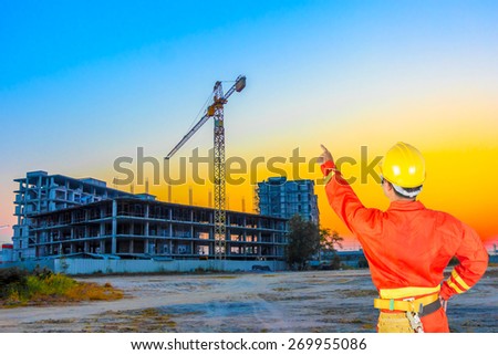 technician and pointing at building construction site against beautiful sky sunset