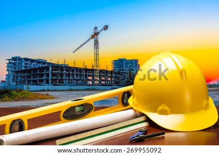 engineer working table plan and blueprint at building construction site against beautiful sky sunset