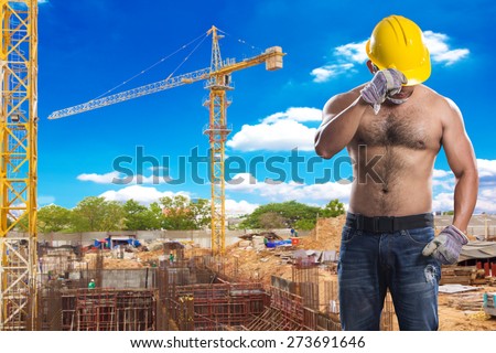strong construction worker at footing of building construction site with tower crane and blue sky
