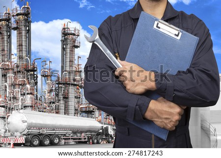 mechanic holding a clipboard of service order with wrench for working at petrochemical oil refinery