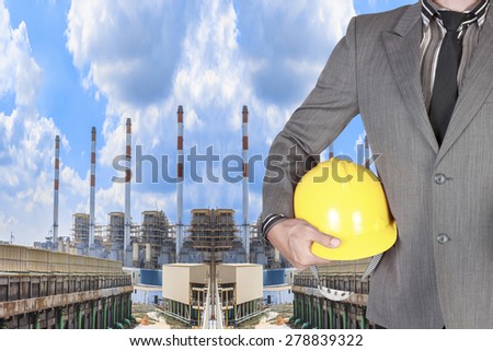 Engineer holding hard hat for working at Industrial power plant with cloud sky