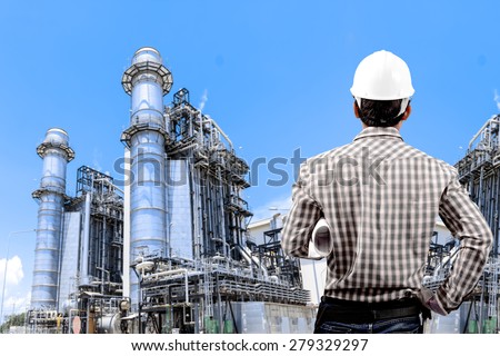 Engineer holding hard hat and blueprint for working at equipments and machinery with modern thermal power plant in refinery
