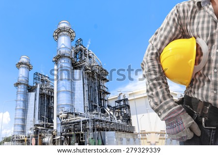 Worker holding hard hat for working at equipments and machinery with modern thermal power plant in refinery