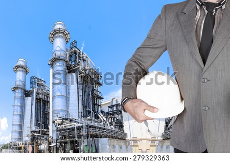 Engineer holding hard hat for working at equipments and machinery with modern thermal power plant in refinery