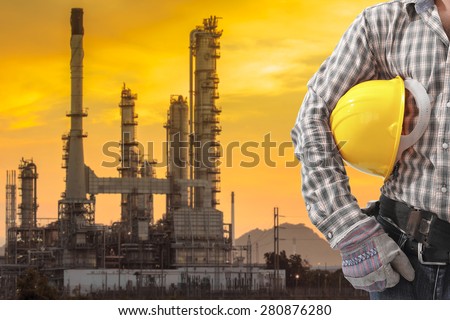 Technician holding hard hat for working at petrochemical oil refinery in beautiful sunrise