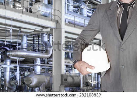Engineer holding hard hat for working with equipments and machinery in a modern thermal power plant