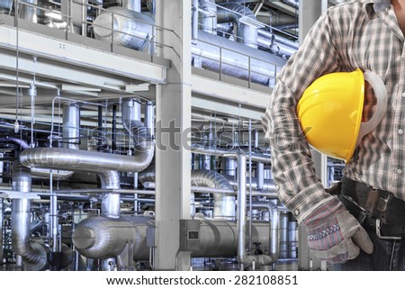 Worker holding hard hat for working with equipments and machinery in a modern thermal power plant