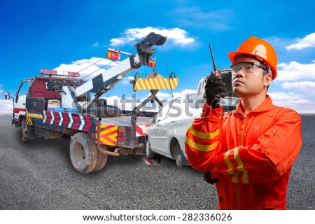 Worker with radio communication in action for working at heavy duty truck used for towing accident saloon car on the road