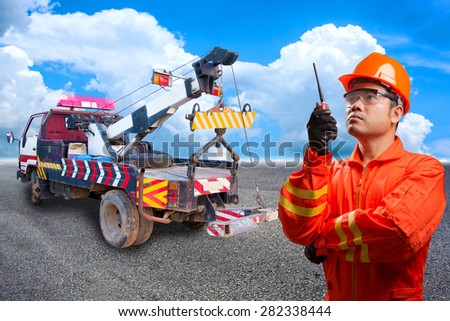 Worker with radio communication in action for working at heavy duty truck used for towing car on the road
