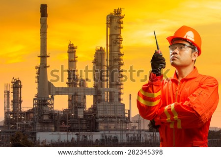 Engineer with radio communication in action for working at petrochemical oil refinery in beautiful sunrise