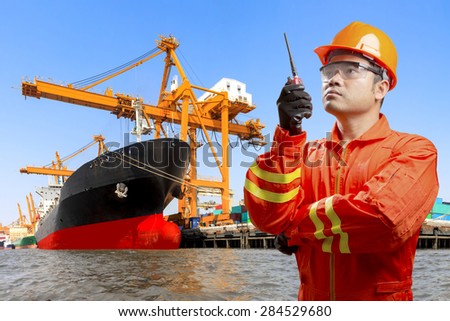 dock worker with radio communication in action for controlling work process commercial ship loading container in shipping port export nautical vessel transport and industry logistic in the harbor