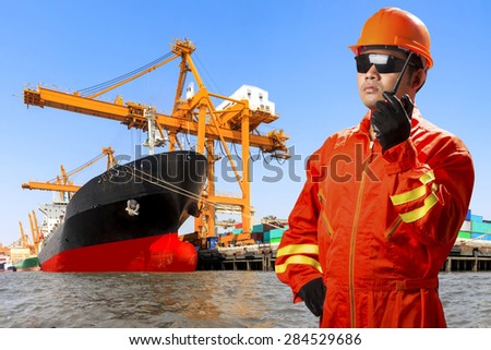 dock worker with radio communication for controlling work process commercial ship loading container in shipping port export nautical vessel transport and industry logistic in the harbor