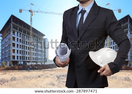 Civil engineer holding blueprint for control working at building construction site
