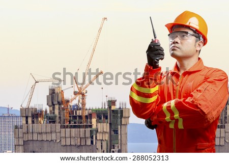 Technician with radio communication in action control working at high building construction site